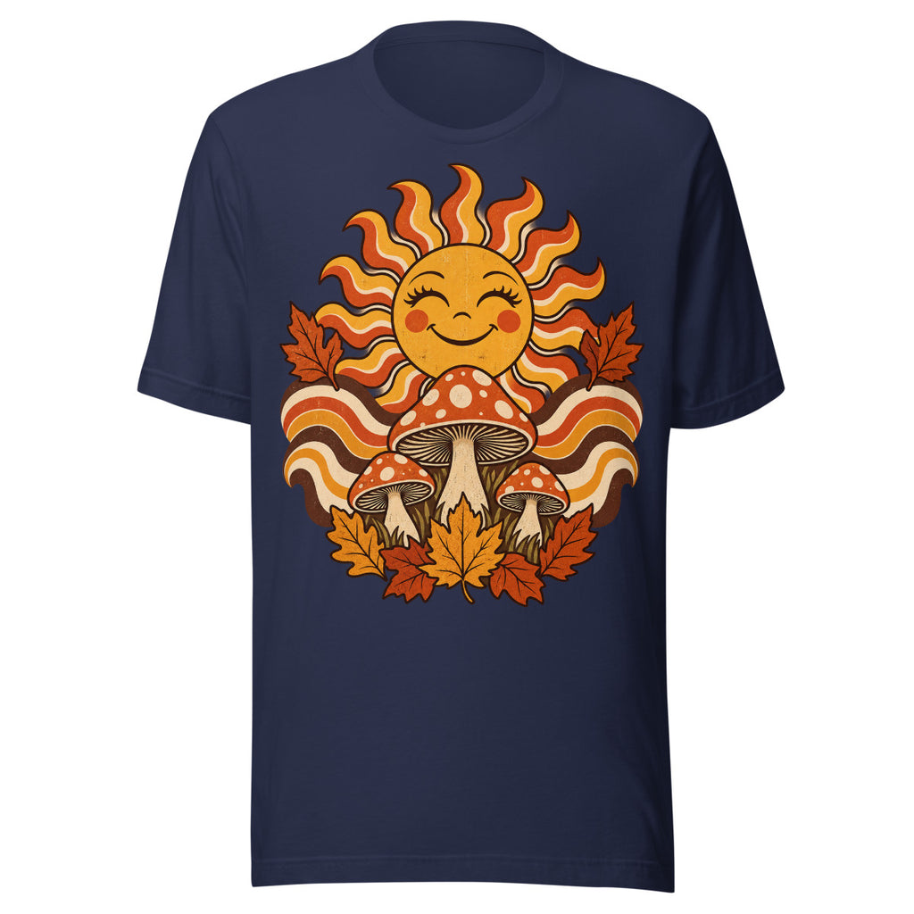 Lächelnde Sonne mit geschwungenen Strahlen, drei rot-weiß gepunktete Fliegenpilze und orange-braunes Herbstlaub vor welligem Hintergrund. – Unisex Staple T-Shirt | Bella + Canvas 3001